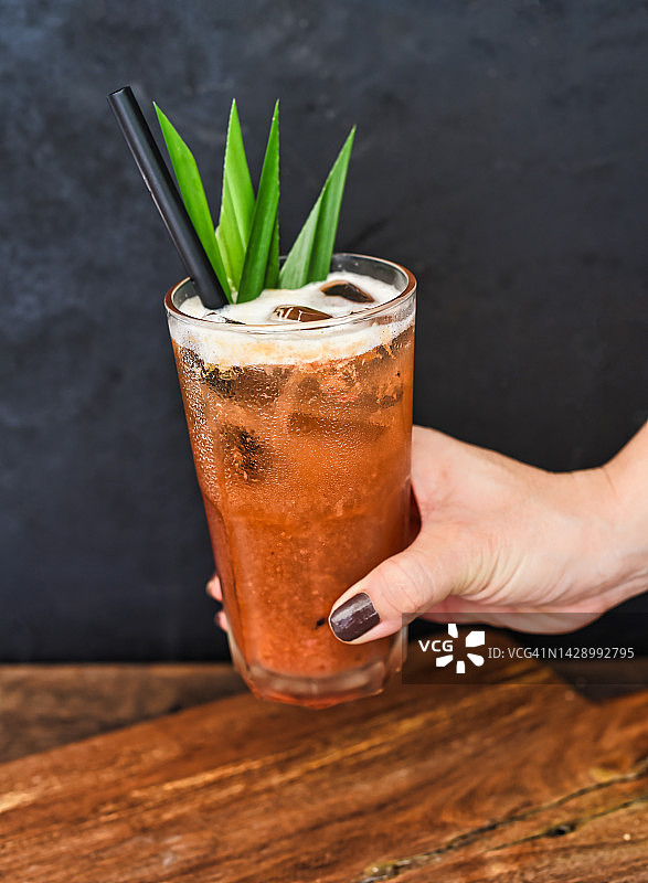 手持冰镇热带茶，绿茶橙子果酱，木桌背景图片素材