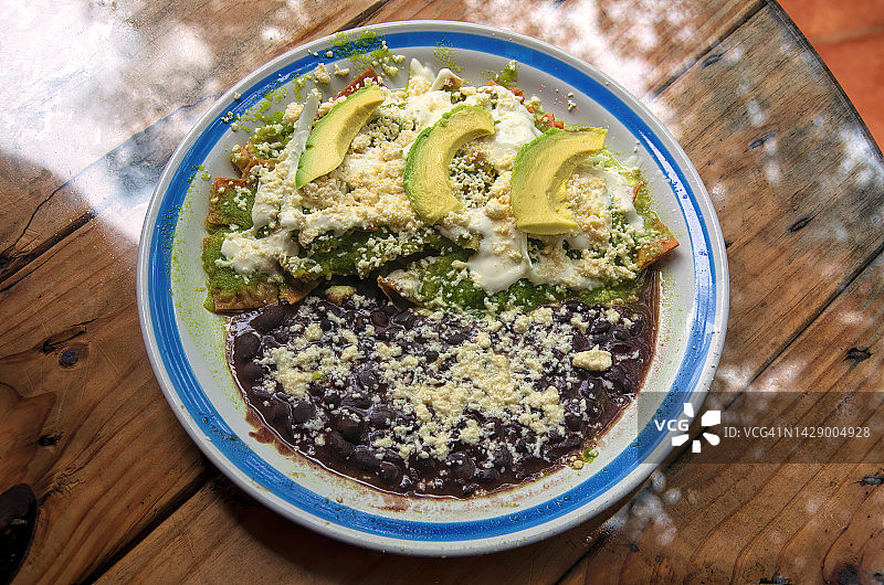 配绿色萨尔萨酱、科蒂哈奶酪、奶油、洋葱、鳄梨和炸黑豆的奇拉基莱斯图片素材