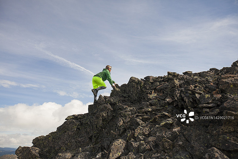 年轻男孩攀登加拿大不列颠哥伦比亚省梅里特山坡岩石的侧视图图片素材