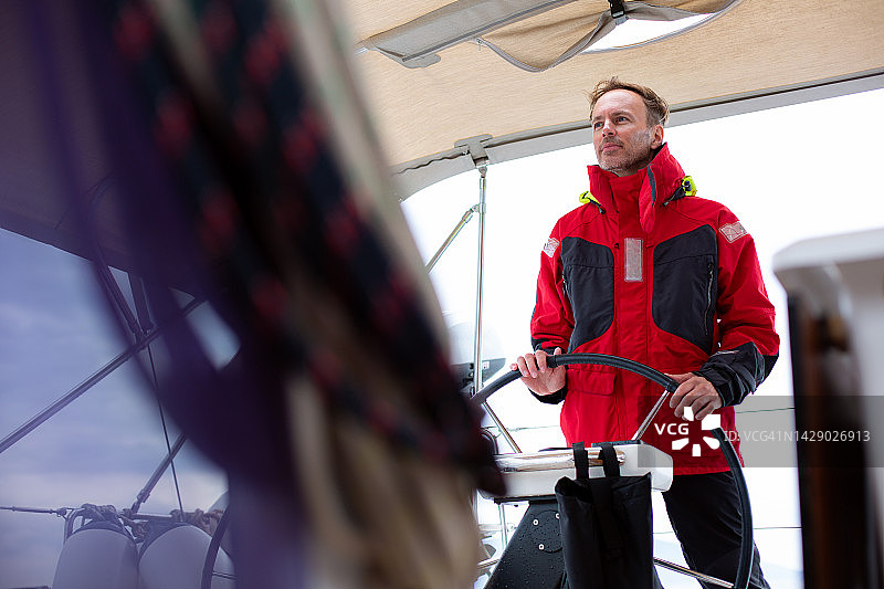 穿着防风衣掌舵游艇的船长图片素材