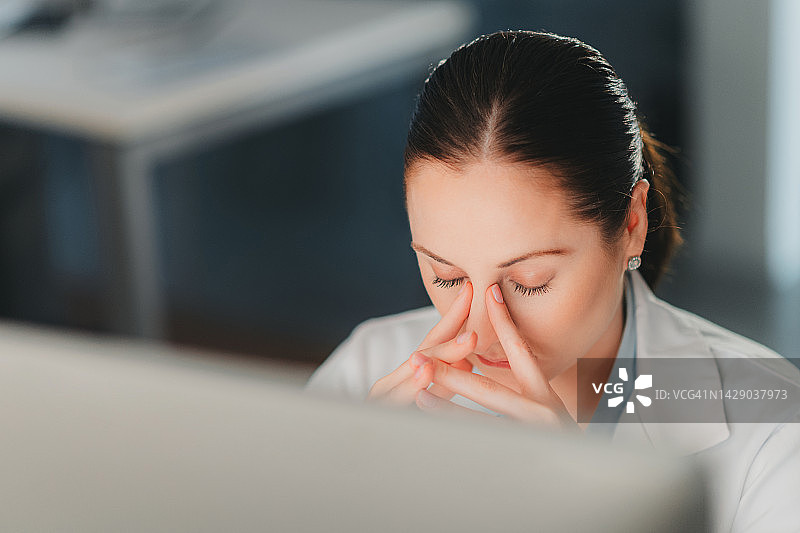 工作中的女人，因压力而双手抱头，在办公室度过糟糕的一天后感到沮丧和疲惫图片素材