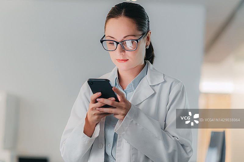 戴眼镜穿实验服的女科学家看手机图片素材