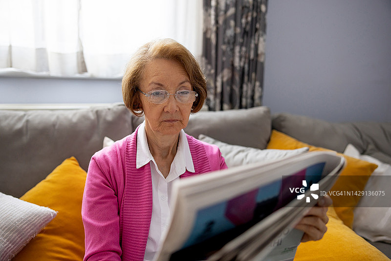 在家阅读报纸的年长女人图片素材