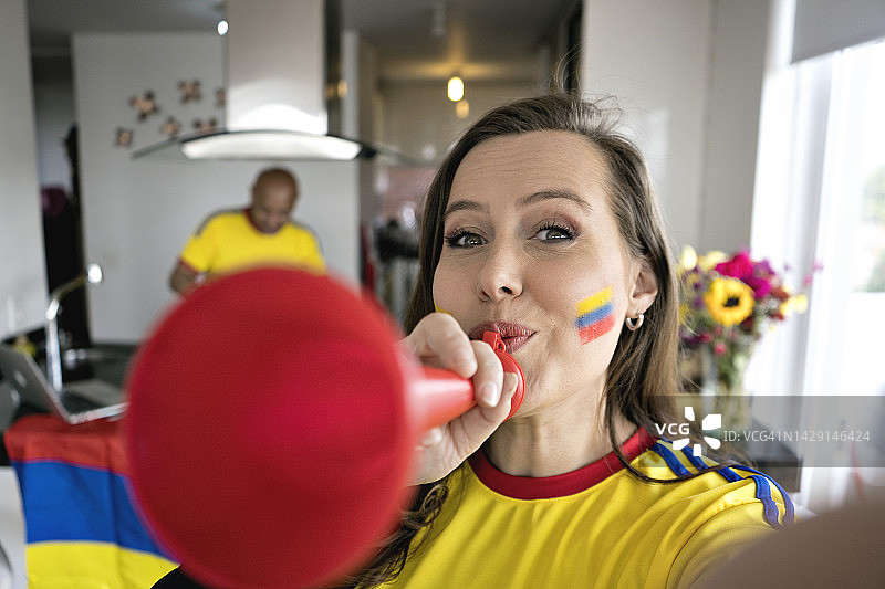 在家穿着哥伦比亚国家队球衣用手机自拍的漂亮女人图片素材