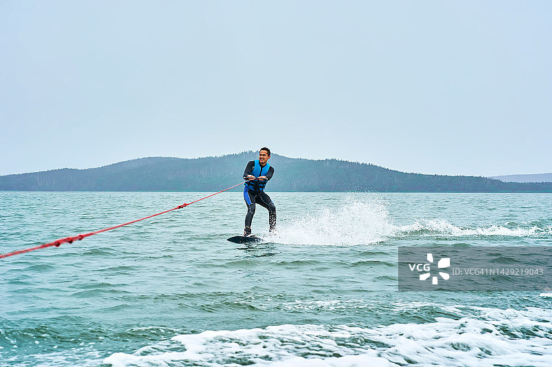 在湖上玩尾波滑水的年轻男人图片素材