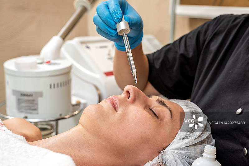 专业美容师在女性脸上滴美容精华图片素材