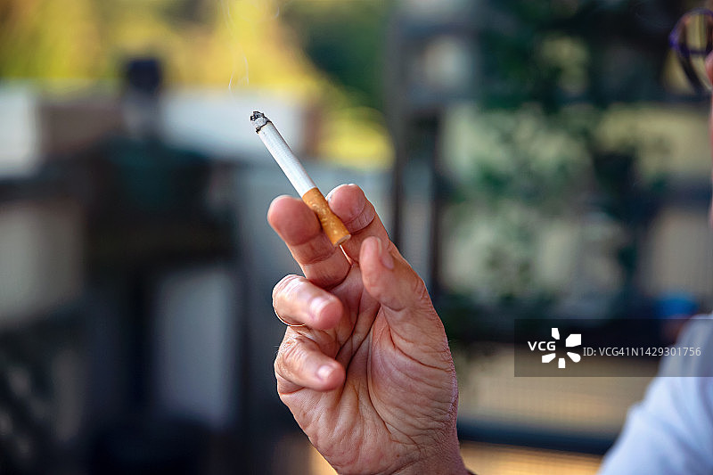 手指夹着点燃的香烟的手部特写图片素材