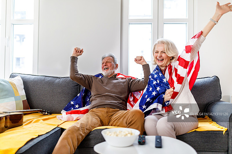一对快乐的美国老年夫妇在家观看体育比赛图片素材