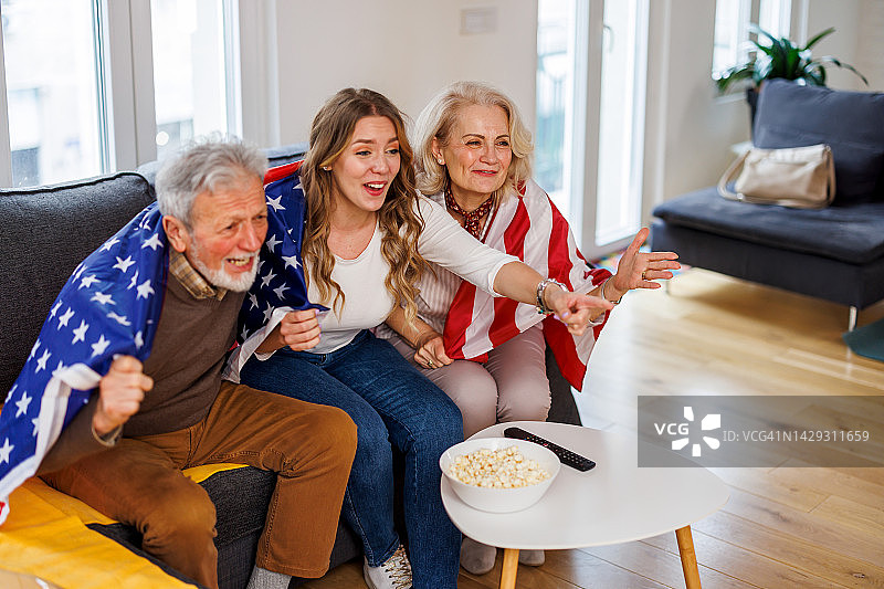 老年夫妇和孙女在家中支持足球队图片素材