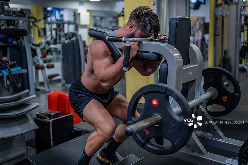 男人在健身房的哈克深蹲机上做股四头肌锻炼图片素材