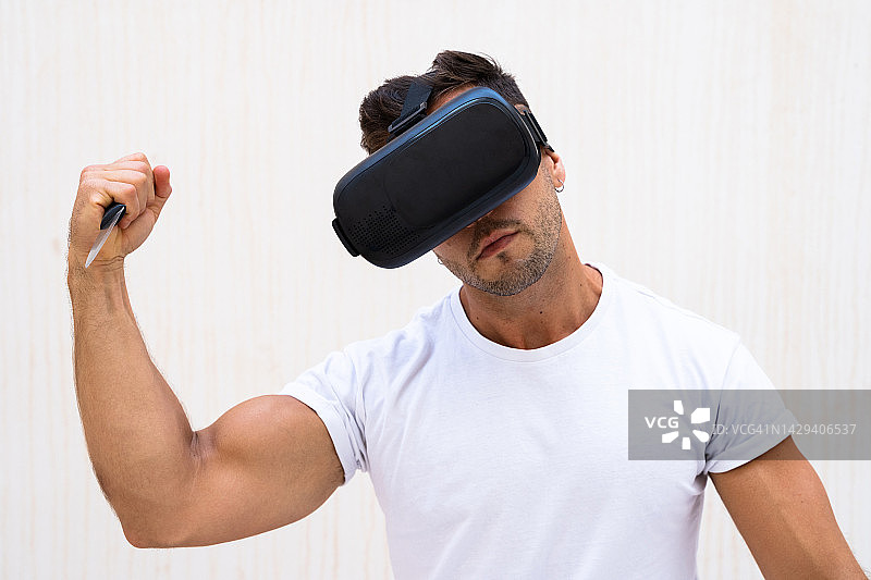 男子佩戴VR眼镜沉浸在虚拟世界中，手持刀——虚拟现实概念图片素材