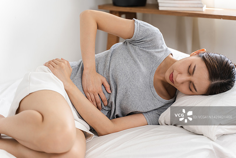年轻女人因胃痛或月经疼痛而难受。图片素材