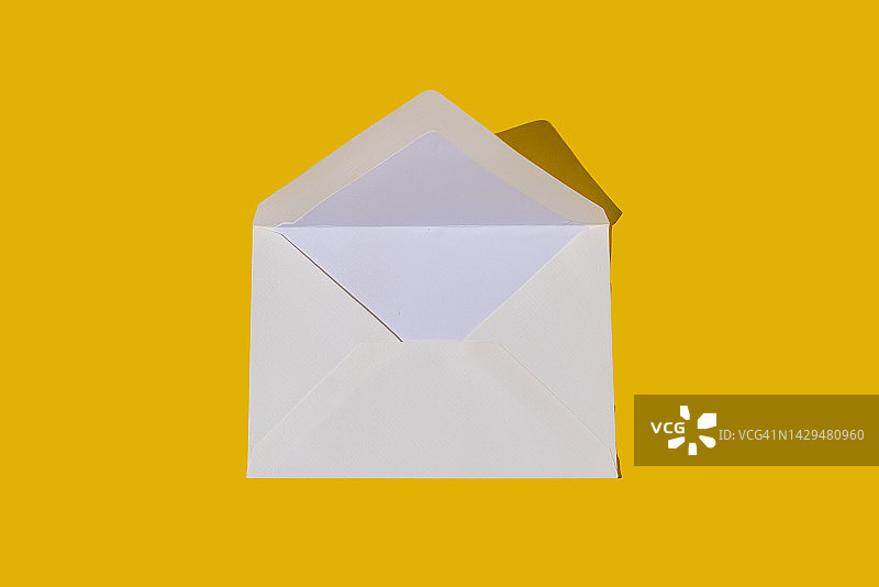 黄色背景上的白色纸质信封，硬阴影，信件、发送、邀请概念图片素材