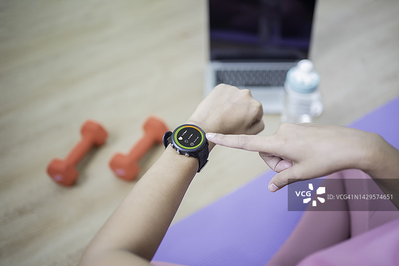 年轻女人使用智能手表上的健身追踪应用展示心率和脂肪燃烧数据图片素材