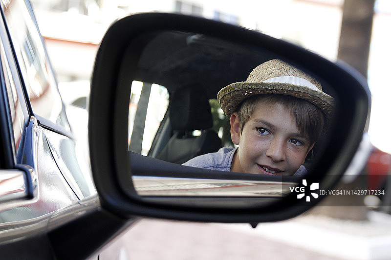 从汽车后视镜中看到的快乐男孩的倒影图片素材