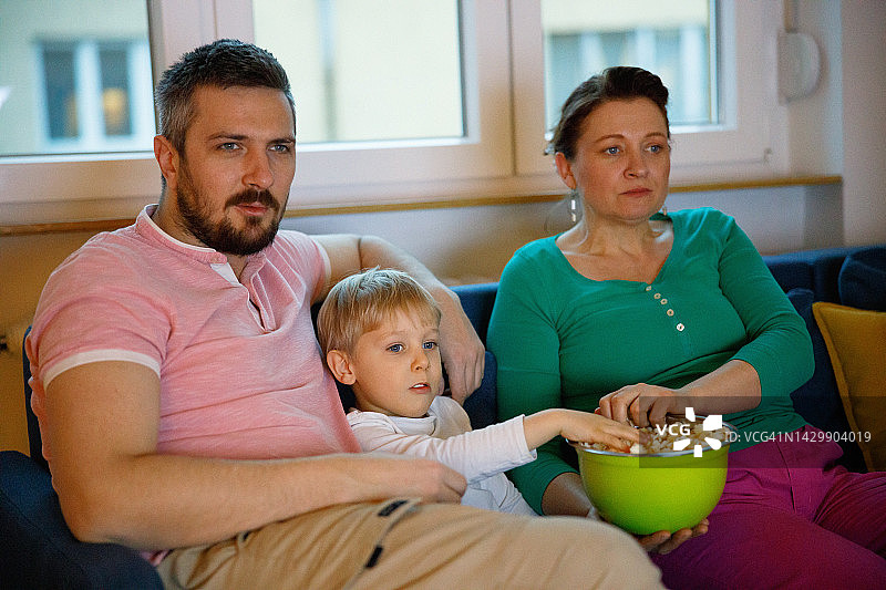一家三口在沙发上看电视吃爆米花图片素材
