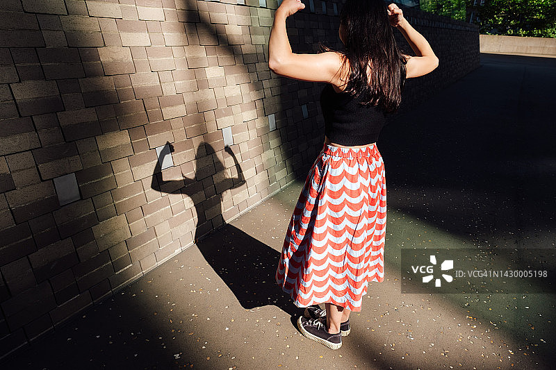 年轻女子自信地站在户外，展示手臂图片素材