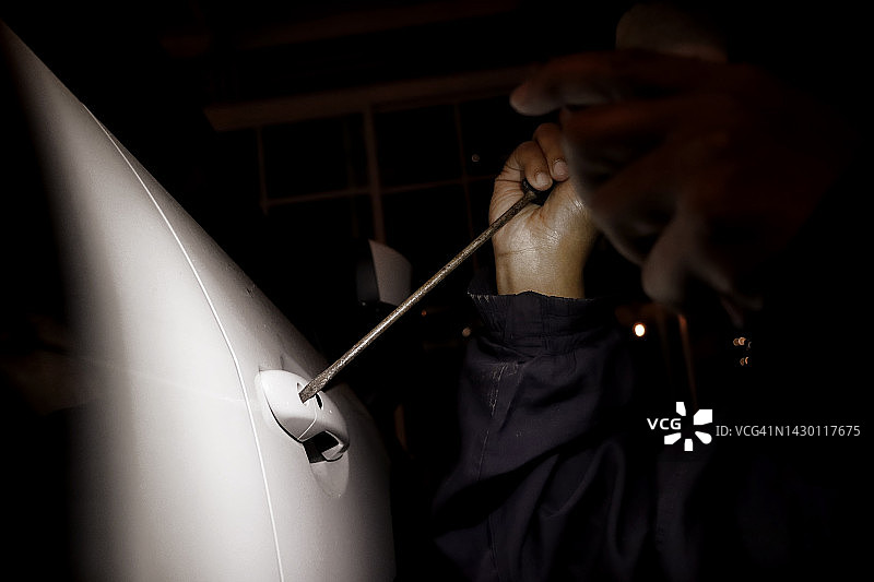 戴着手套的男人用螺丝刀撬车图片素材