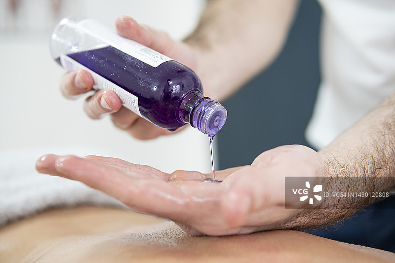 白人男子在手上涂按摩油，准备为顾客按摩图片素材