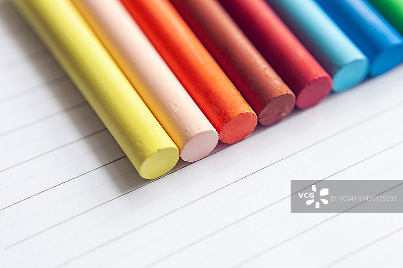 彩色蜡笔在条纹纸上对角线排列的特写镜头图片素材