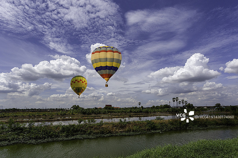 蓝天下，乡村上空五彩缤纷的热气球图片素材