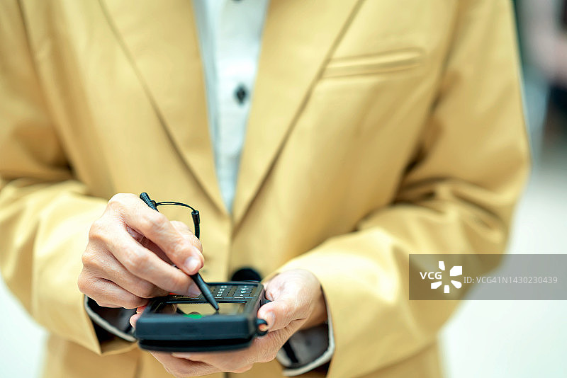 商务女性在信用卡读卡器中输入客户数据，准备收款的特写图片素材
