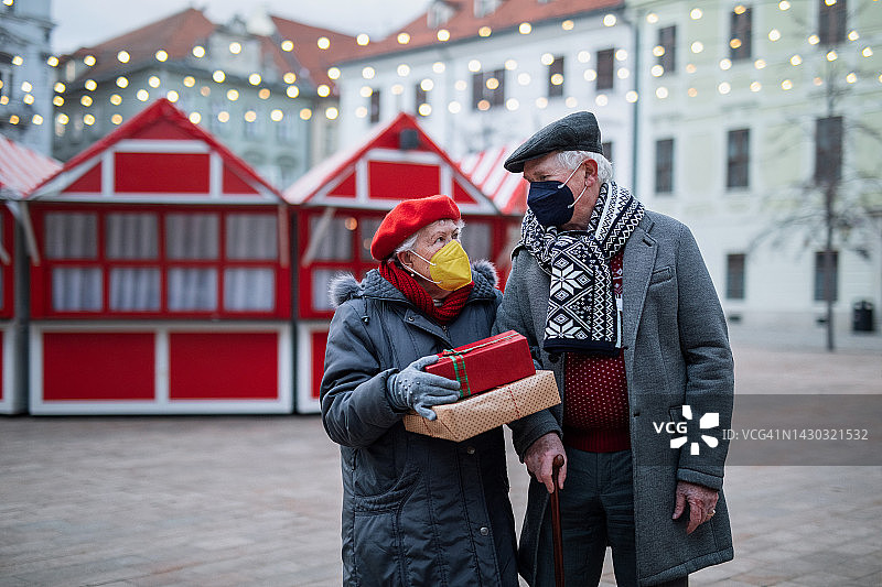 年长的夫妇戴着FFP2口罩在圣诞市场购买礼物图片素材