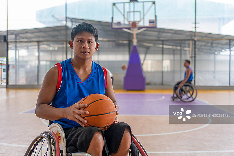 坐在轮椅上在空地上 holding ball的篮球运动员图片素材
