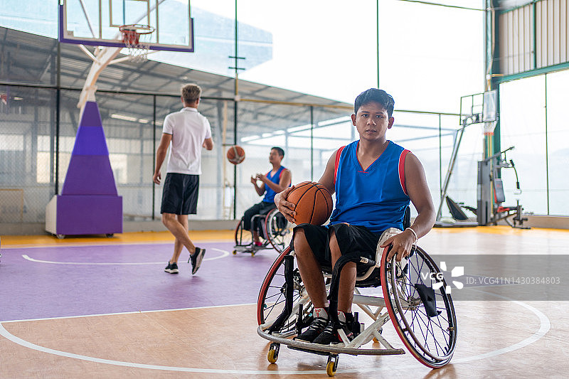 坐在轮椅上在空地上 holding ball的篮球运动员图片素材