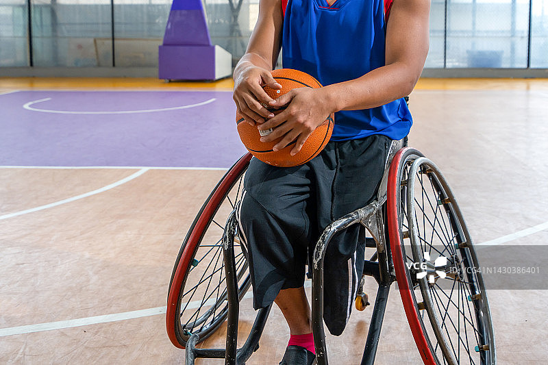 坐在轮椅上在空地上抱着篮球的篮球运动员图片素材