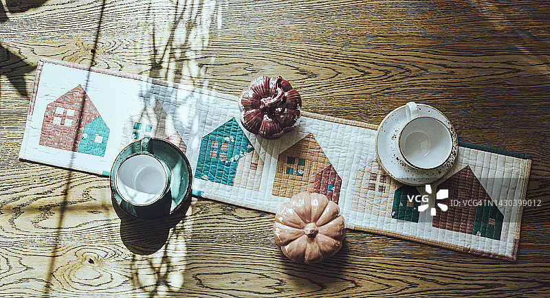 秋季房屋拼布桌旗，米绿色陶瓷南瓜木桌背景，空咖啡杯图片素材