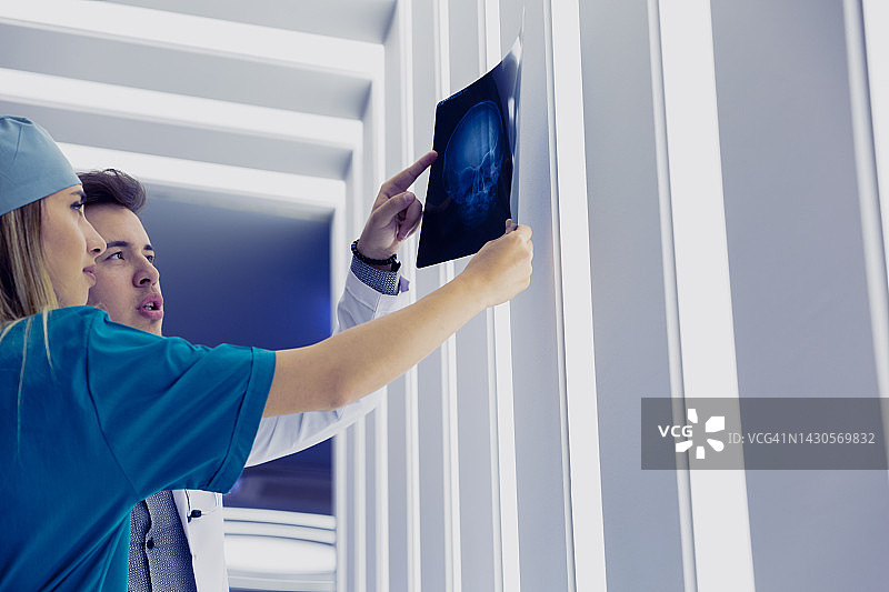 年轻的医护专业人员正在看病人的头骨X光片图片素材