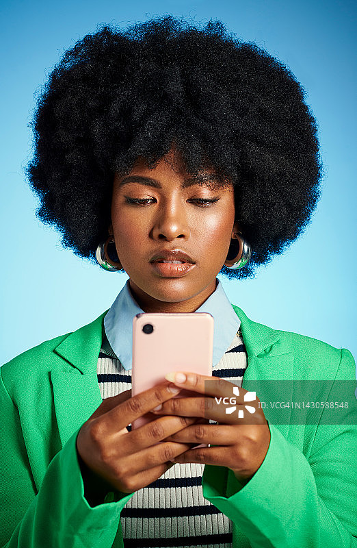 黑人女性用手机阅读社交媒体、新闻或在线帖子，并通过短信联系，背景为蓝色模拟演播室。在互联网上使用带有5G的移动智能手机应用程序的非洲模特图片素材