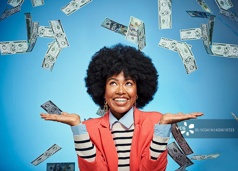 黑人女性在蓝色背景下展示金融投资成功，现金如雨下图片素材