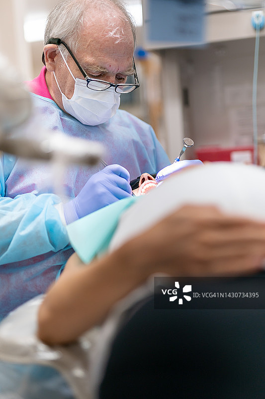 经验丰富的牙医为成年女性患者进行口腔护理图片素材