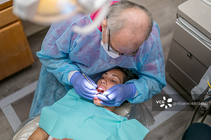 经验丰富的牙医为成年女性患者进行口腔护理图片素材