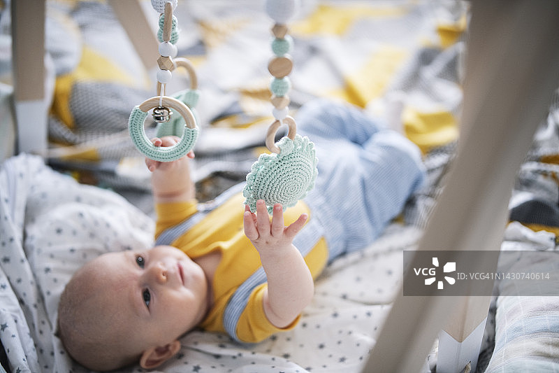 玩木制悬挂玩具的好奇宝宝图片素材