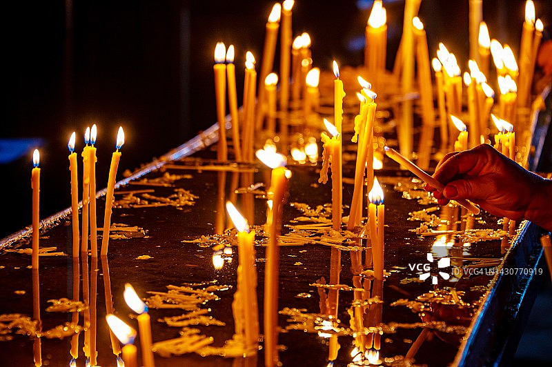 人手在亚美尼亚格加尔德修道院洞穴教堂点燃蜡烛图片素材