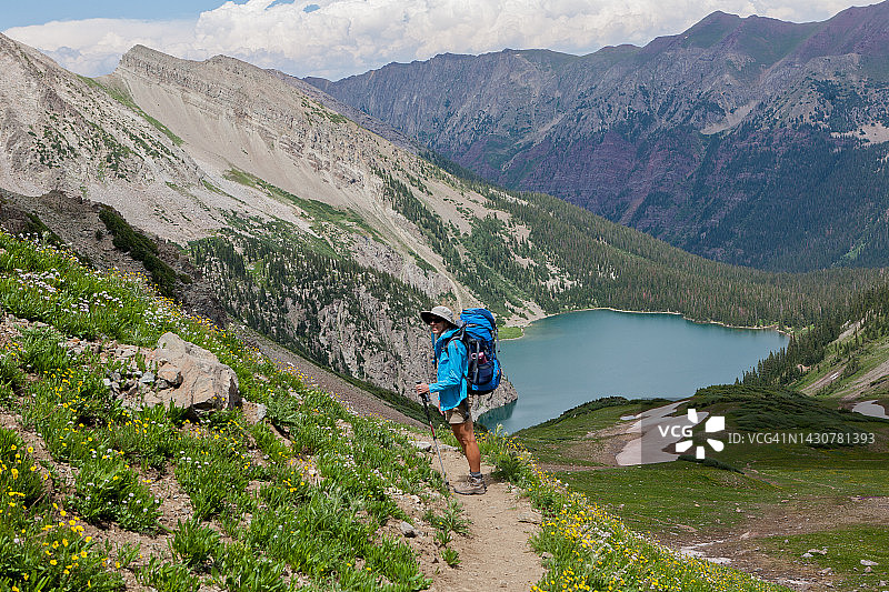 年长的女背包客在科罗拉多州阿斯彭四通环线雪堆湖上方的小路上徒步。图片素材