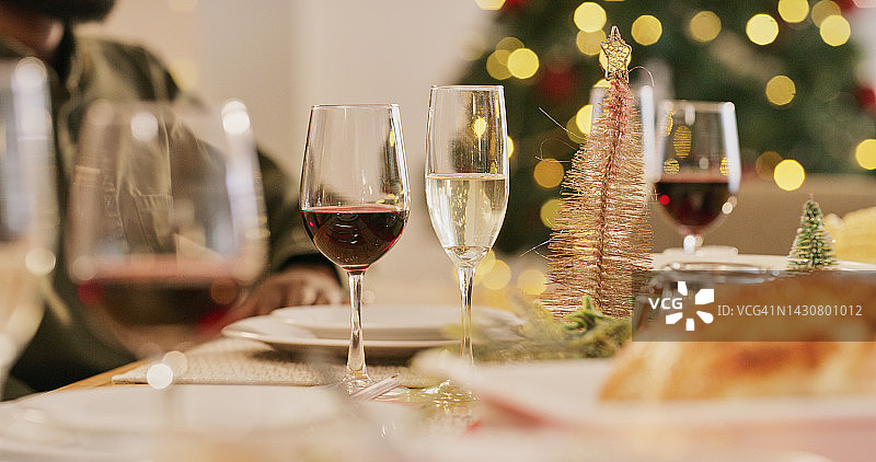 圣诞派对庆祝的香槟和红酒杯，在房屋或餐厅的餐桌上与散景树灯。食物和酒精饮料，用于聚会、社交聚会或庆祝节日图片素材