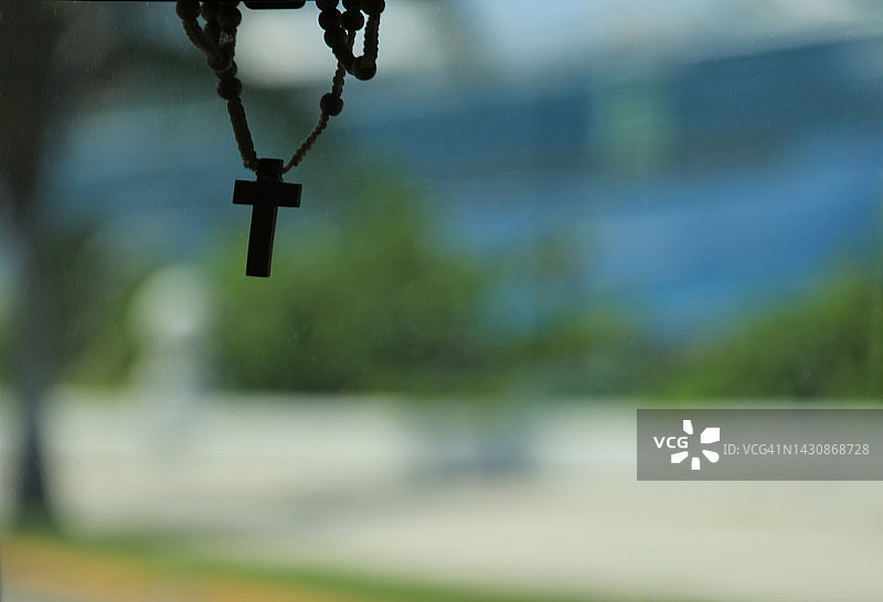 车辆内的圣玫瑰念珠苦像，背景是挡风玻璃图片素材