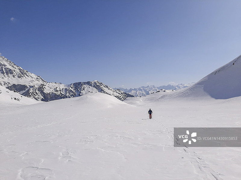 在雪地地形中徒步的远方男子图片素材
