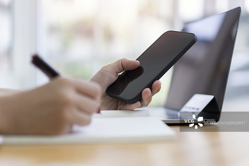 商务人士手持智能手机工作，在工作区书写商务细节图片素材