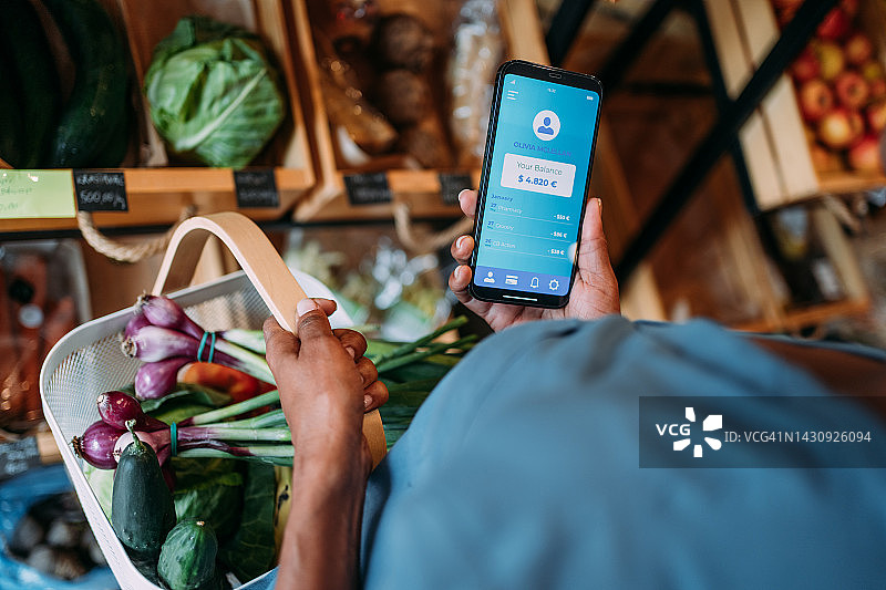 年轻女人在有机商店购物时使用智能手机应用查看财务图片素材