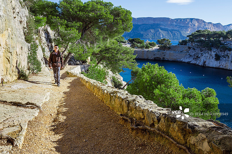 男子沿着法国普罗旺斯-阿尔卑斯-蓝色海岸卡西斯莱卡兰克海滨小路行走图片素材