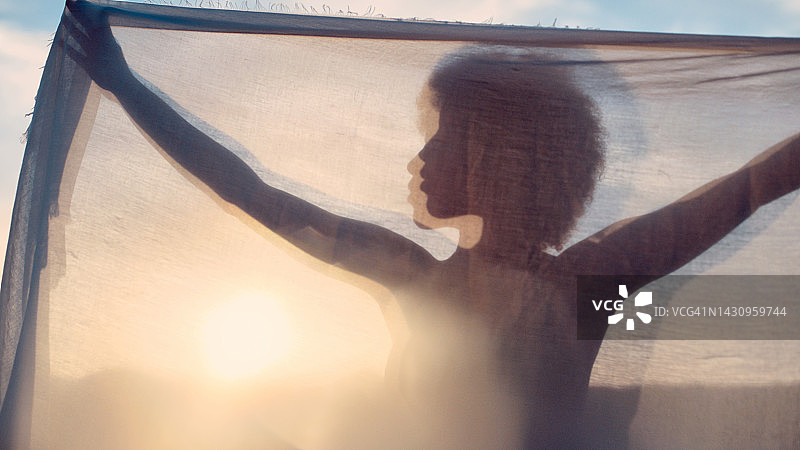 海滩日落时窗帘后女人的轮廓模糊人像图片素材