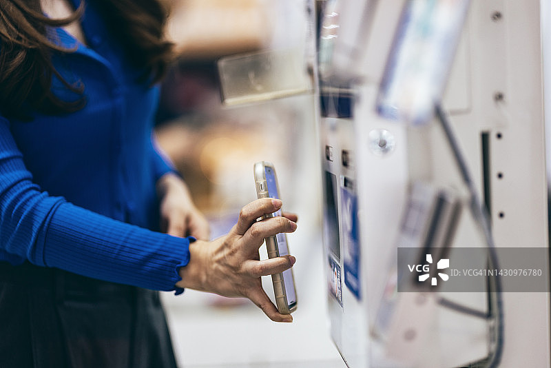 年轻的亚洲女性在超市使用智能手机进行非接触式支付图片素材
