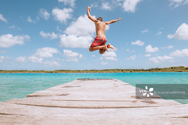 快乐的年轻人从码头跳入美丽的湖中图片素材