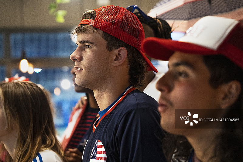 一群年轻朋友在拥挤的酒吧观看美国国家队比赛图片素材