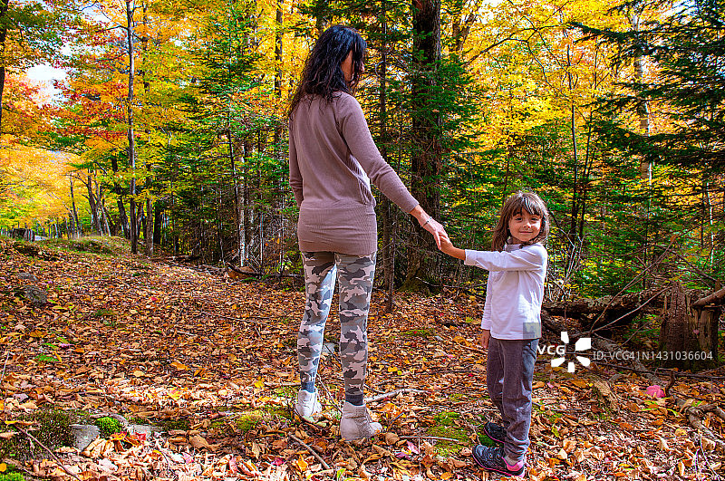快乐的母女在树叶繁茂的季节里沿着小路散步图片素材